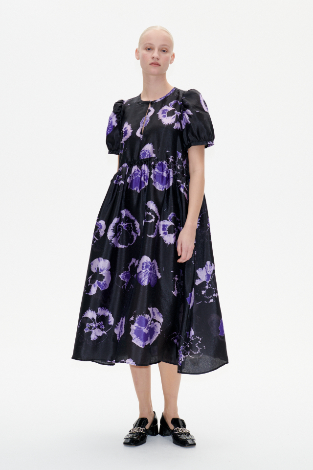 Artemis Dress Purple Pansy This midi-length dress features a button closure with keyhole opening at the front, pockets at the sides, slight puffing at the skirt, and a dipped waistline - model image