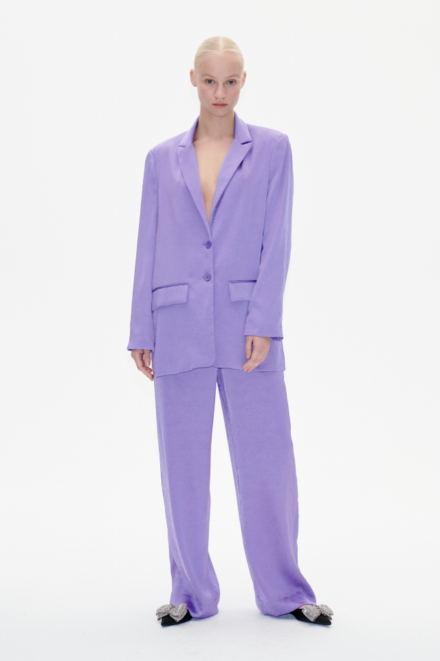 Narine Trousers Dahlia Purple These fluid, wide-leg trousers feature an elasticated waistband, side pockets, and raised seams down the sides - model image