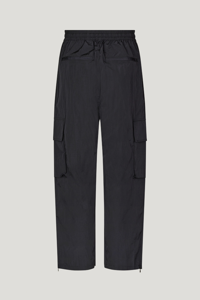 Nemu Trousers black These high-rise, nylon trousers feature an elasticated waistband with a drawstring, zip pockets at the sides, cargo pockets on the legs, and zips at the ankles - back image